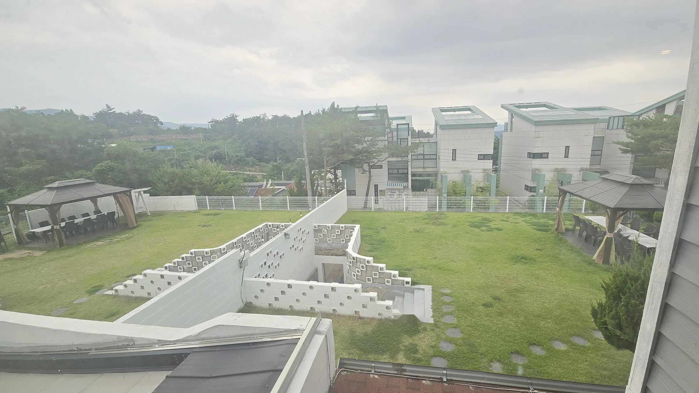 안개 낀 날 위에서 내려다본 잔디마당과 두 채의 독채, 정자