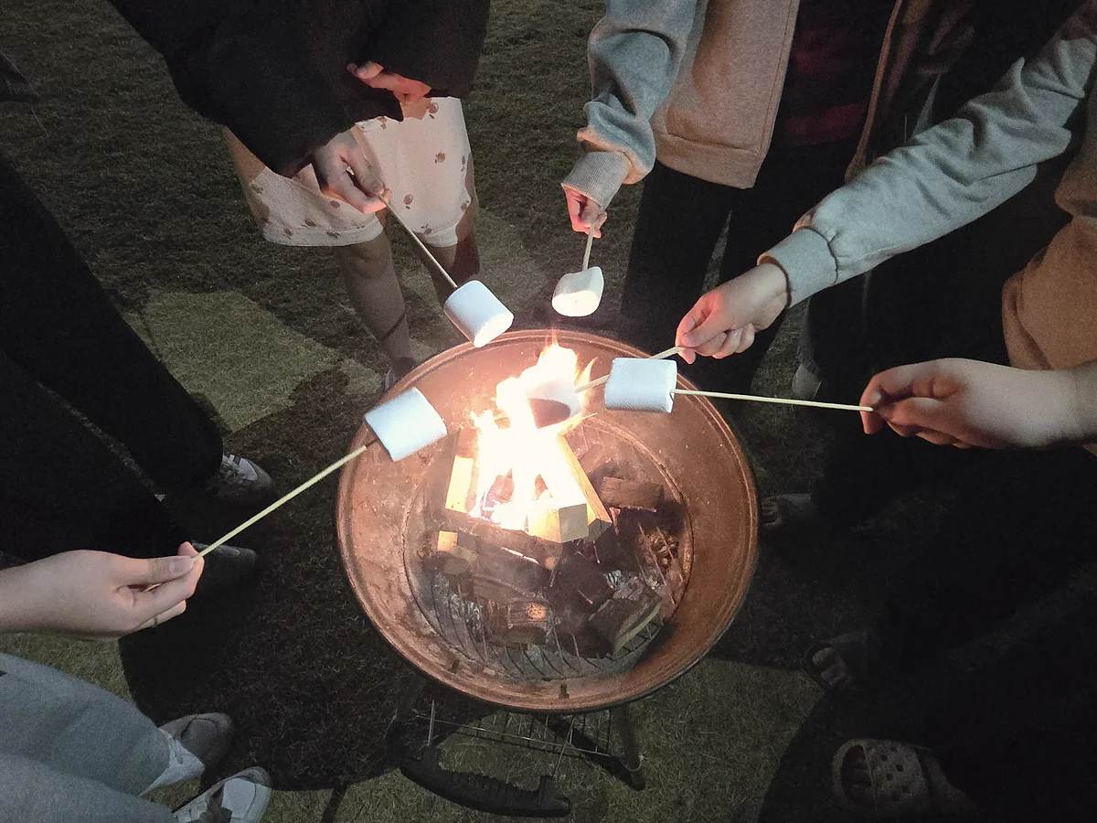모닥불 위에서 마시멜로를 굽는 손들